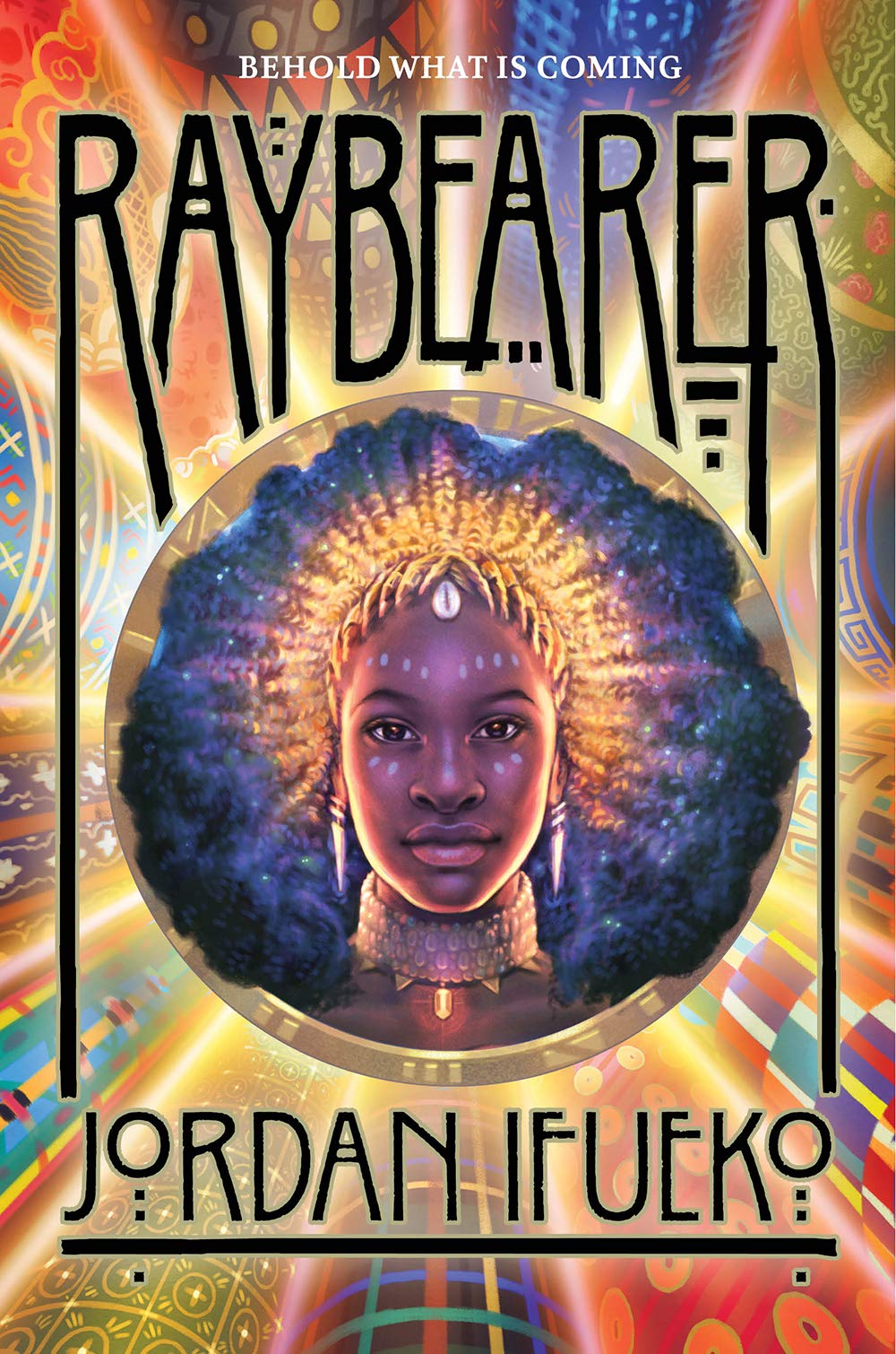 It's the cover of the book. At the very top of the image there's the title (Raybearer) in black while at the very bottom there's the author's name (Jordan Ifueko). The background is a pattern made up of different coloured rays (some gold, some red, some blue) whereas in the middle there is an image of a young black woman with her black hair fanned out around her. On her head she is wearing a golden tiara in the shape of rays that emanate out.
